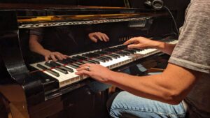 Jay Frost at Cue Recording Studio with hands reflecting in Yamaha piano