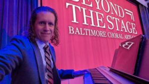 Pianist Jay Frost positioned on a raised stage at the M&T Bank Exchange, prepared for the Baltimore Choral Arts Society performance.